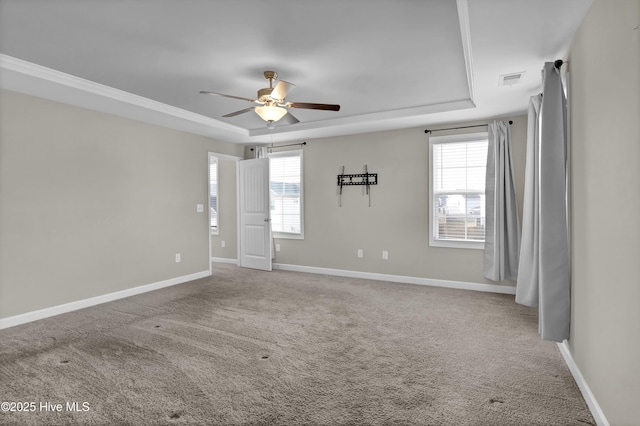 carpeted spare room with a healthy amount of sunlight, baseboards, a raised ceiling, and ceiling fan