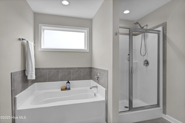 bathroom with a shower stall, a bath, and recessed lighting