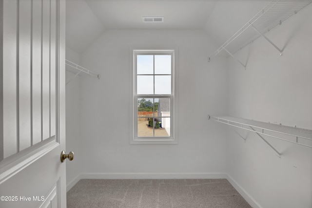 walk in closet featuring visible vents, carpet flooring, and lofted ceiling