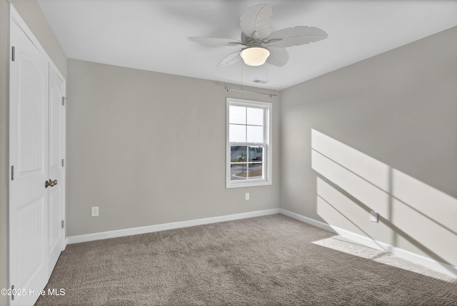 empty room featuring visible vents, baseboards, ceiling fan, and carpet flooring