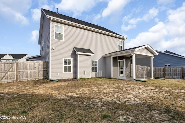 back of property featuring a fenced backyard and a sunroom