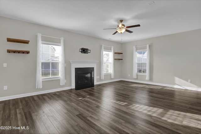 unfurnished living room featuring a fireplace with flush hearth, baseboards, dark wood-type flooring, and ceiling fan