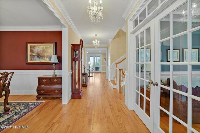 hallway with crown molding, wood finished floors, french doors, and a notable chandelier