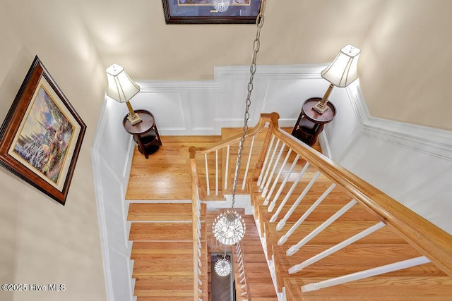 stairs with a decorative wall and a wainscoted wall