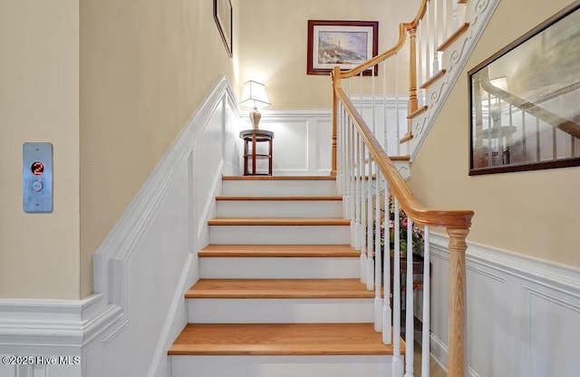 stairs featuring a wainscoted wall and a decorative wall