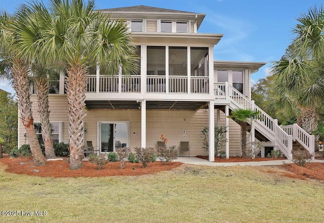 back of house with a yard, a sunroom, and stairway