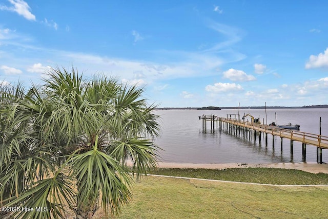 view of dock with a water view, a yard, and boat lift