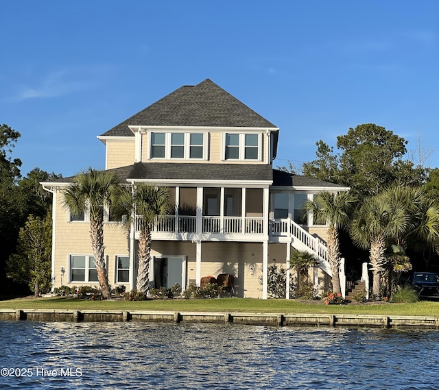 rear view of property with a water view, a shingled roof, and uncovered parking