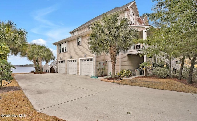 view of property exterior with a water view, stairs, a garage, and driveway