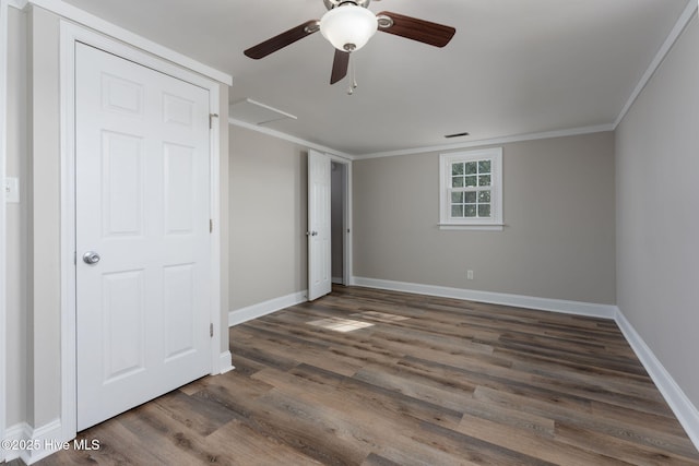 unfurnished bedroom featuring a ceiling fan, baseboards, ornamental molding, dark wood-type flooring, and visible vents