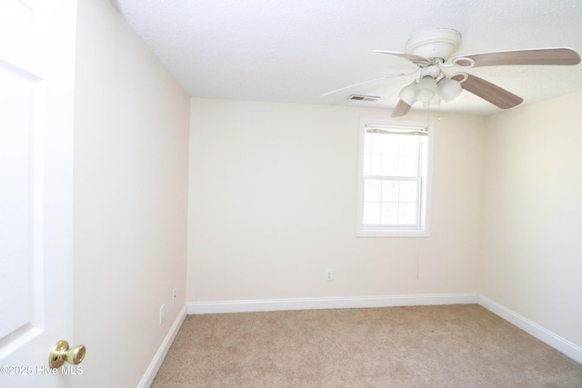 unfurnished room with visible vents, light carpet, baseboards, and ceiling fan