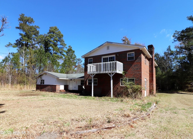 exterior space featuring brick siding, a chimney, and a front yard