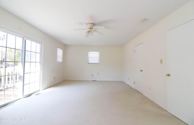 unfurnished room featuring light colored carpet, visible vents, and ceiling fan