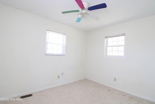 unfurnished room with light colored carpet, baseboards, visible vents, and a ceiling fan