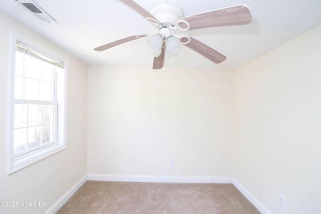 empty room featuring ceiling fan, baseboards, visible vents, and light carpet