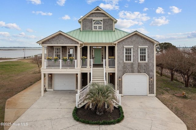 raised beach house with stairs, a garage, covered porch, and driveway