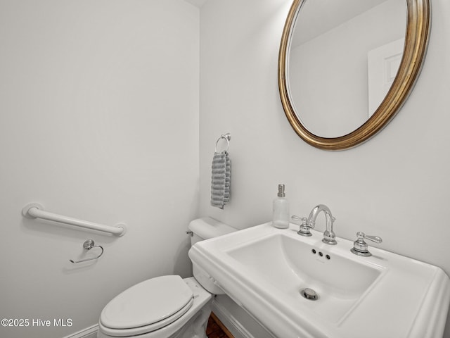 half bathroom featuring toilet, baseboards, and a sink