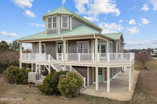 back of property featuring stairway, covered porch, metal roof, a garage, and a standing seam roof