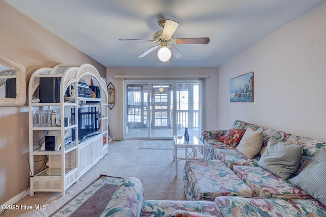 carpeted living area featuring a ceiling fan and baseboards