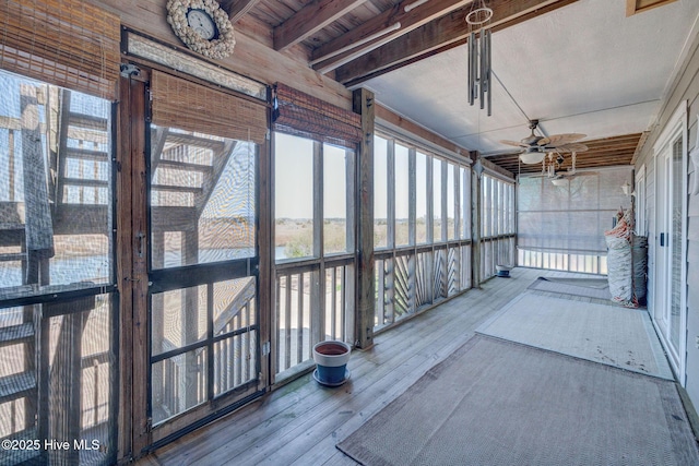 unfurnished sunroom featuring beamed ceiling and a ceiling fan