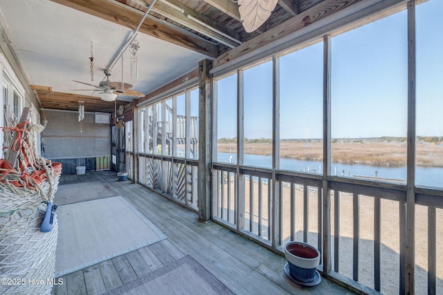 unfurnished sunroom featuring a ceiling fan and a water view