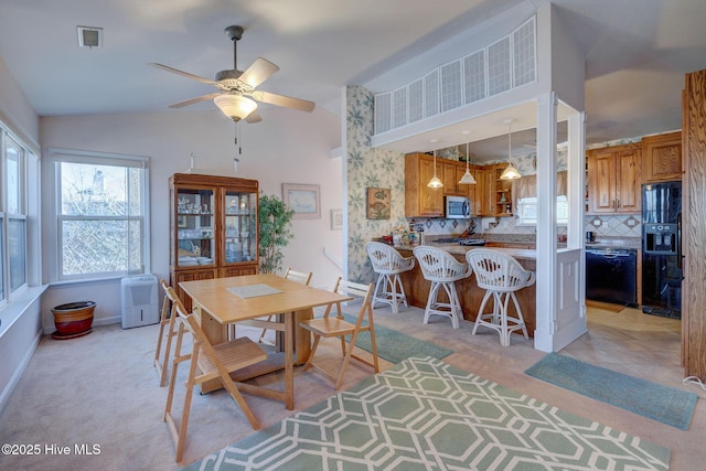 dining room featuring a ceiling fan, visible vents, baseboards, lofted ceiling, and light carpet