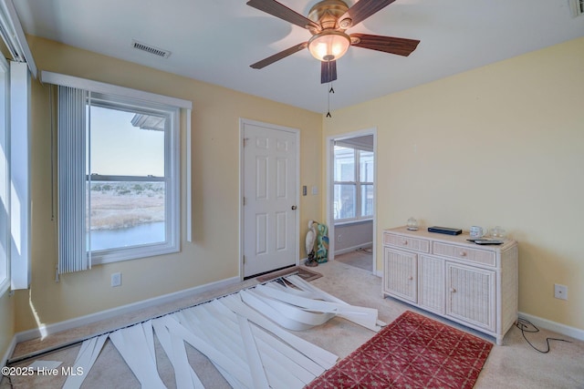 entrance foyer with light carpet, visible vents, a healthy amount of sunlight, and ceiling fan