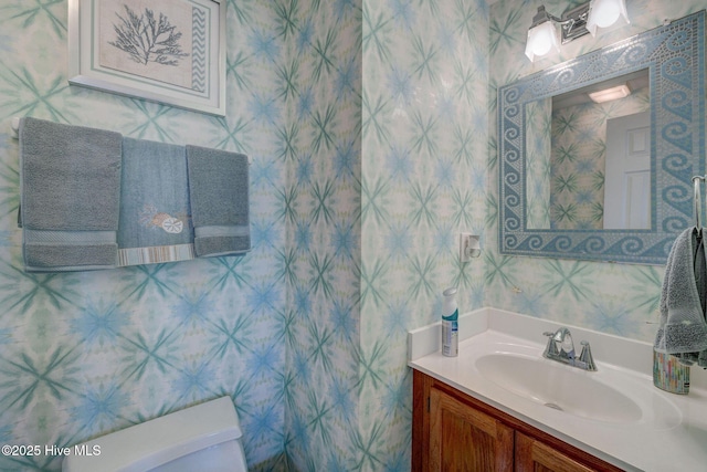 bathroom featuring wallpapered walls, toilet, and vanity