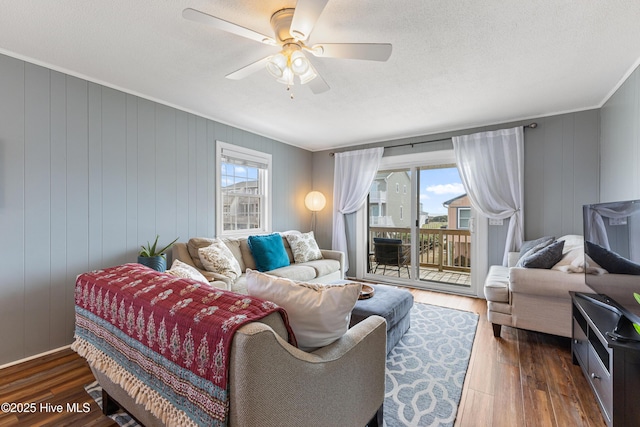 living room featuring dark wood finished floors, a healthy amount of sunlight, crown molding, and a ceiling fan