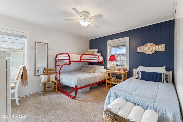 bedroom with multiple windows, a ceiling fan, carpet floors, and a textured ceiling