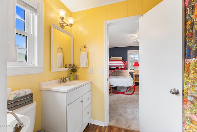 ensuite bathroom with toilet, ornamental molding, wood finished floors, connected bathroom, and vanity