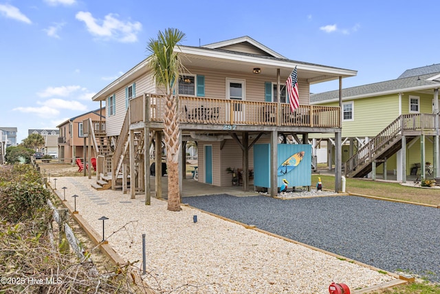 rear view of property with a carport, gravel driveway, and stairs