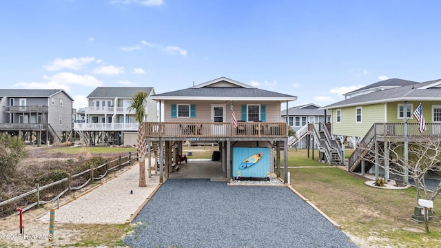 view of front of house featuring driveway, stairs, a carport, a front lawn, and a residential view