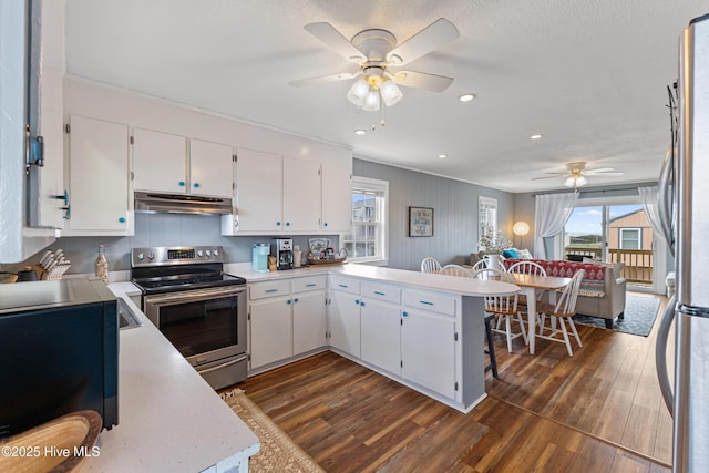 kitchen with under cabinet range hood, a peninsula, appliances with stainless steel finishes, light countertops, and ceiling fan