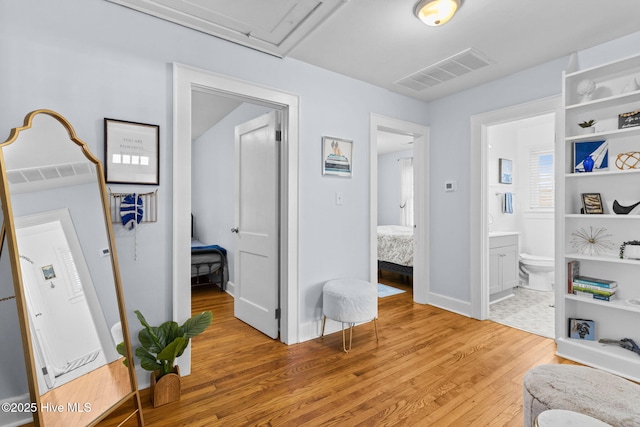 corridor with baseboards, visible vents, and light wood-style floors