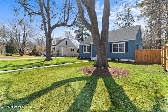 view of front of house featuring a shingled roof, fence, and a front lawn