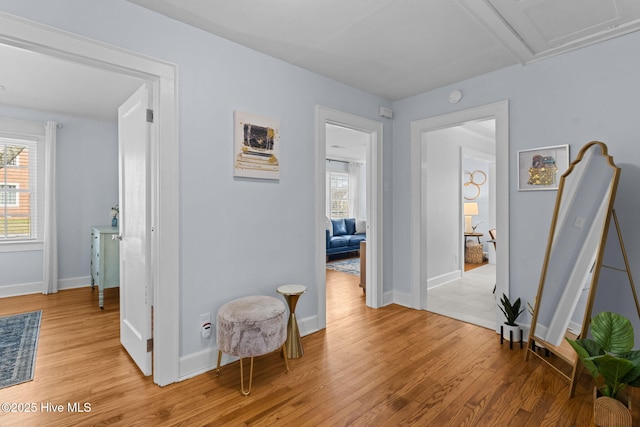 corridor with light wood-style flooring and baseboards