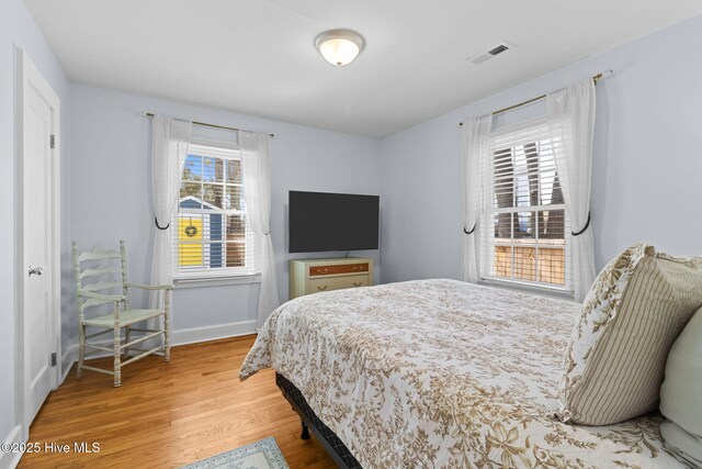 bedroom featuring baseboards, visible vents, and wood finished floors