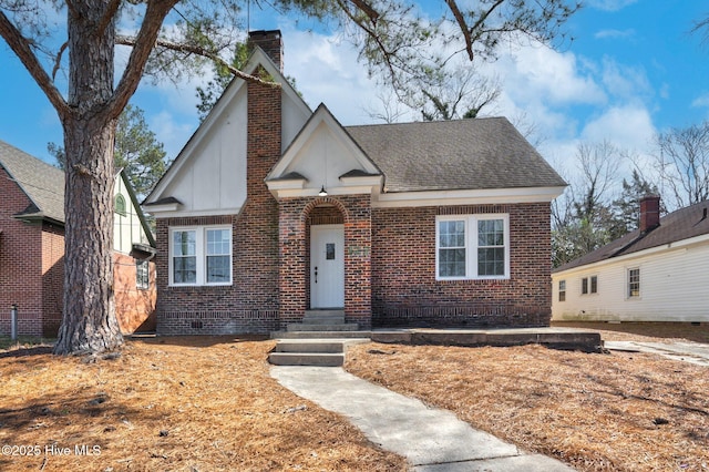 view of front of property featuring brick siding, a chimney, and a shingled roof