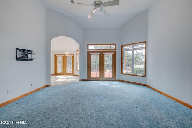 unfurnished room with baseboards, carpet flooring, arched walkways, high vaulted ceiling, and a ceiling fan