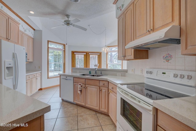 kitchen featuring under cabinet range hood, a sink, white appliances, a peninsula, and vaulted ceiling