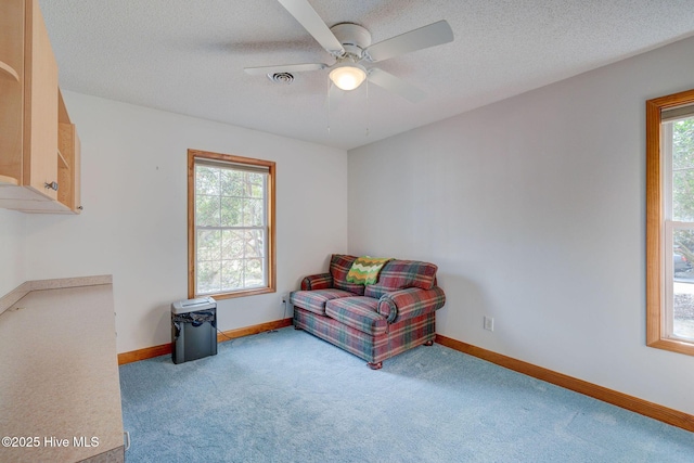 sitting room featuring a wealth of natural light, visible vents, a textured ceiling, and ceiling fan