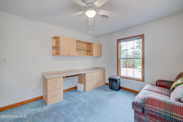 home office featuring built in desk, light colored carpet, baseboards, and ceiling fan