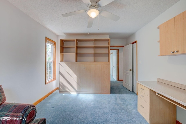 interior space featuring ceiling fan, light carpet, baseboards, and a textured ceiling