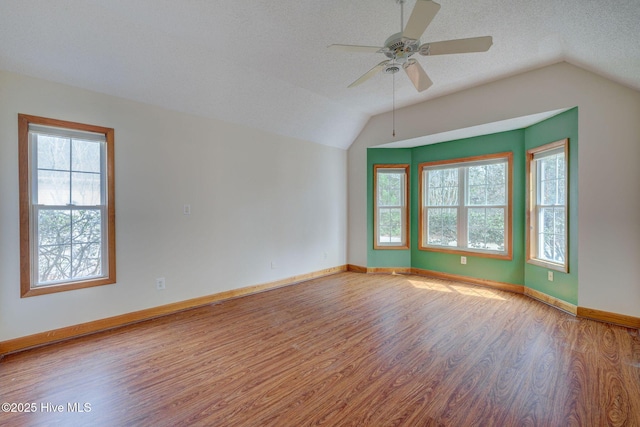 spare room with vaulted ceiling, a textured ceiling, a ceiling fan, and wood finished floors