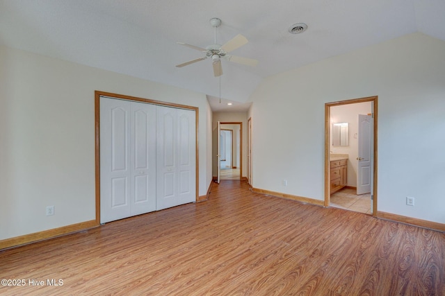 unfurnished bedroom with visible vents, lofted ceiling, light wood-style floors, and a closet