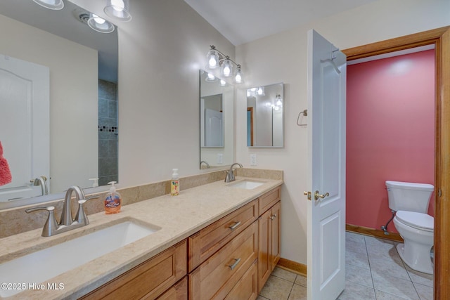 bathroom with a sink, toilet, double vanity, and tile patterned floors