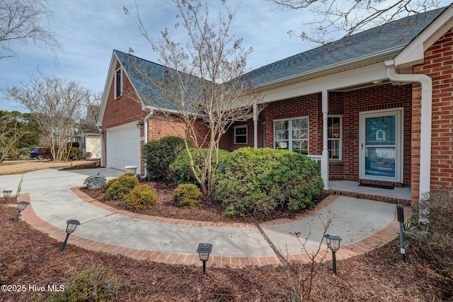 view of side of home with brick siding, driveway, and a shingled roof