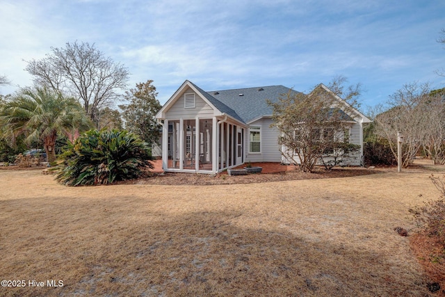 back of house with a yard, roof with shingles, and a sunroom