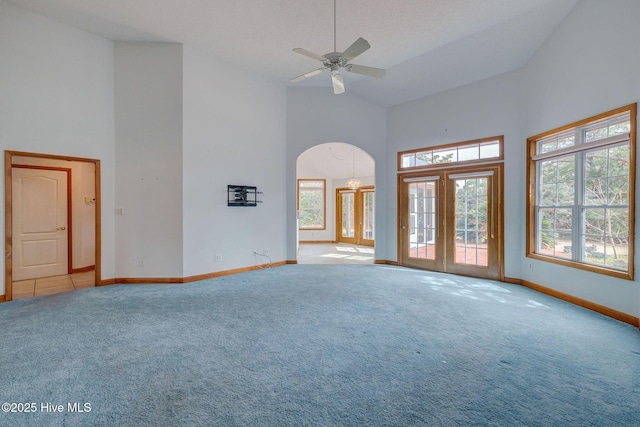 interior space featuring arched walkways, ceiling fan, high vaulted ceiling, and baseboards